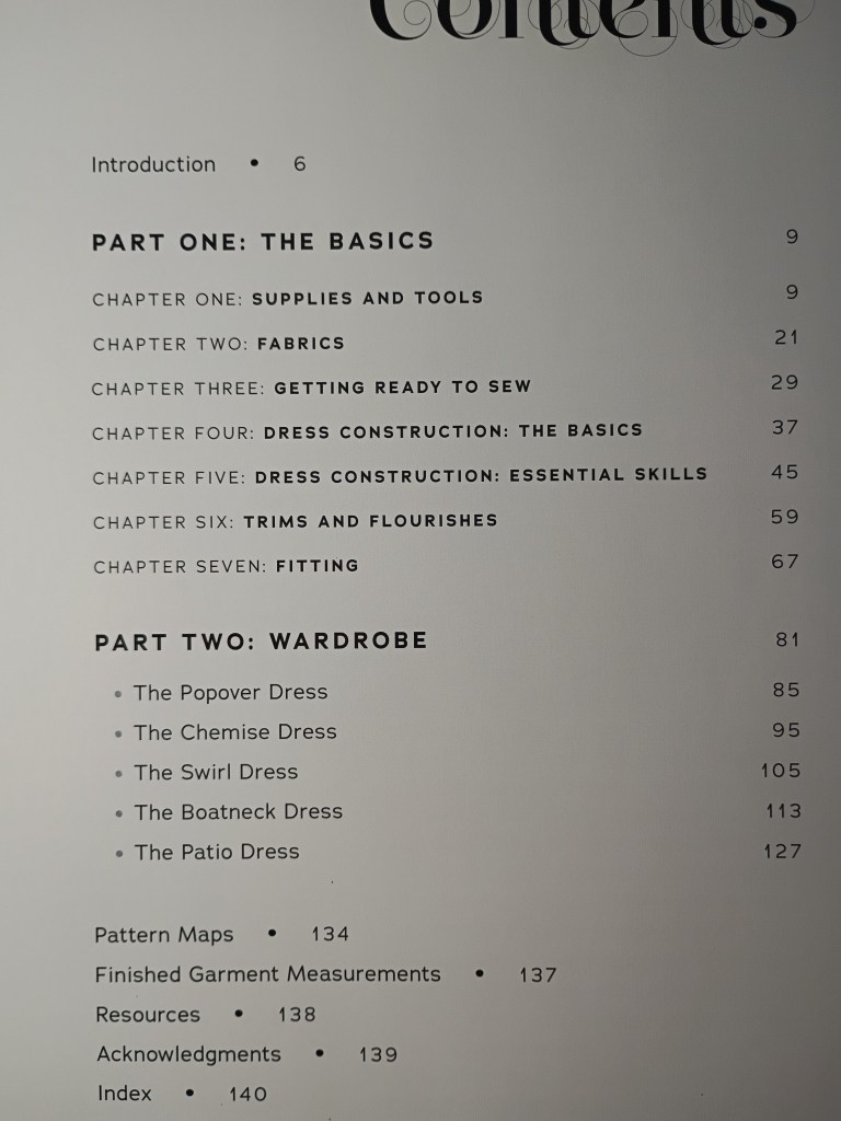 A close-up photograph of the Table of Contents page from the sewing book, detailing the page numbers for Part One: The Basics and Part Two: Wardrobe, including specific dresses like The Popover Dress and The Chemise Dress.